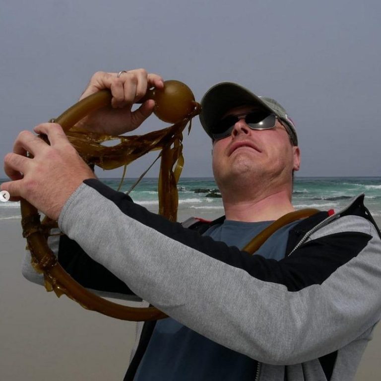 Man sieht Erik, wie er Quatsch macht, am Strand.
